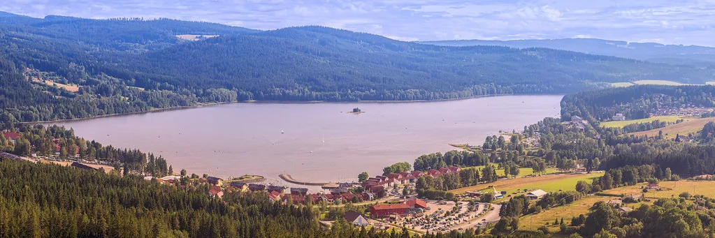 Jezero obklopené zalesněnými kopci s vesnicí u břehu